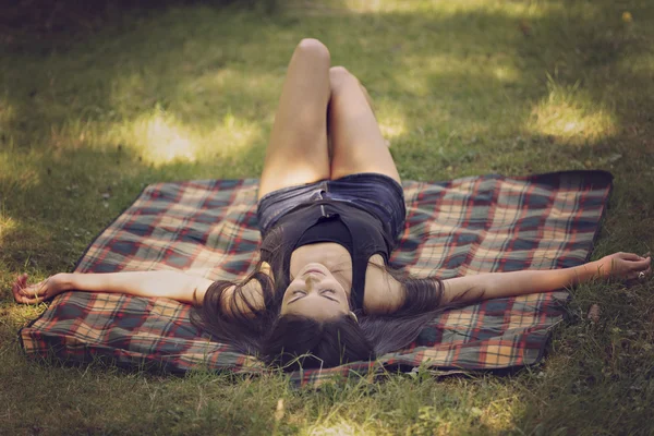 Vacker ung kvinna ligger på en filt och koppla av i naturen — Stockfoto