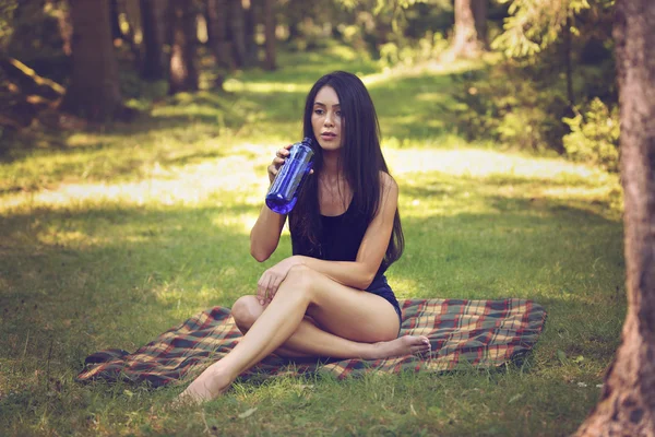 Beautiful woman relaxing and drinking water, sitting in  garden, — Stock Photo, Image