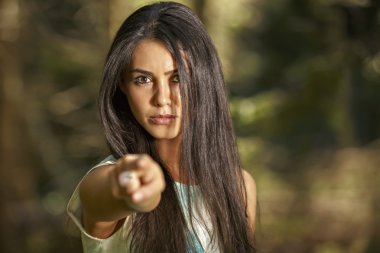 Closeup portrait of young angry woman pointing at someone as if clipart