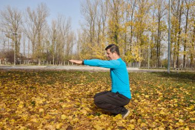 Orta yaşlı bir adam parkta spor için ısınma egzersizleri yapıyor.