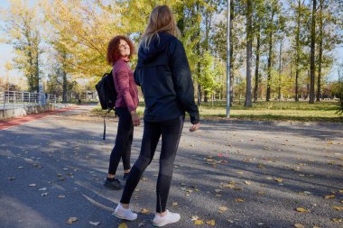 Güzel bir sonbahar gününde arkadaşıyla birlikte spor yapan orta yaşlı bir kadın.