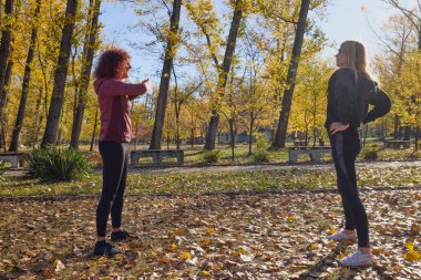 Güzel bir sonbahar gününde arkadaşıyla birlikte spor yapan orta yaşlı bir kadın.