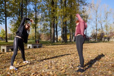 Güzel bir sonbahar gününde arkadaşıyla birlikte spor yapan orta yaşlı bir kadın.
