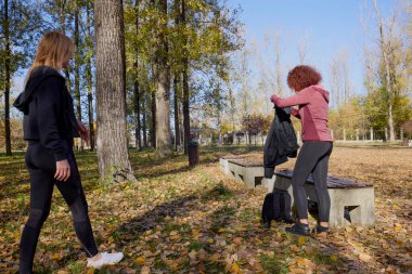 Orta yaşlı bir kadın arkadaşıyla parkta yürüyor, rahatlıyor, sohbet ediyor ve bir şeyler atıştırıyor..