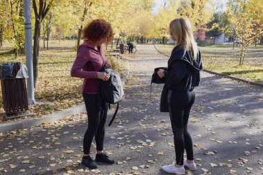 Orta yaşlı bir kadın arkadaşıyla parkta yürüyor, rahatlıyor, sohbet ediyor ve bir şeyler atıştırıyor..
