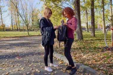 Orta yaşlı bir kadın arkadaşıyla parkta yürüyor, rahatlıyor, sohbet ediyor ve bir şeyler atıştırıyor..