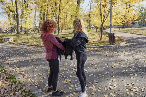 Orta yaşlı bir kadın arkadaşıyla parkta yürüyor, rahatlıyor, sohbet ediyor ve bir şeyler atıştırıyor..