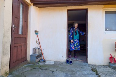 Köyden yaşlı bir kadın ev işleri yapıyor, tavukları besliyor ve onlara bakıyor..