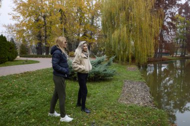 Bir sonbahar günü parkta yürüyen iki orta yaşlı kadın.