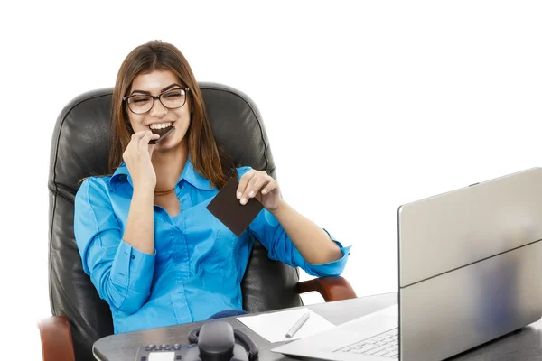 Jonge mooie zakenvrouw eten van chocolade op haar werkplek — Stockfoto