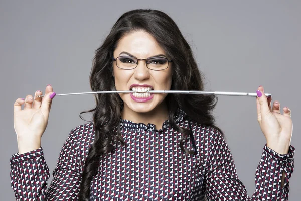 Сердитая женщина в очках, кусающая карандаш — стоковое фото