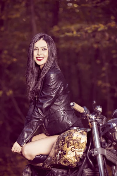 Chica motorista en una chaqueta de cuero en una motocicleta posando en la naturaleza —  Fotos de Stock