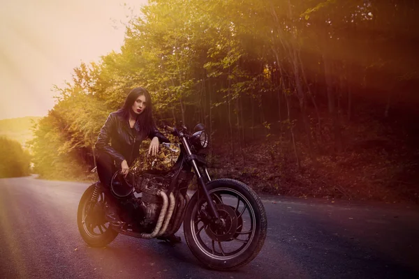 Motorcu kız doğada poz bir motosiklet üzerinde bir deri ceketli
