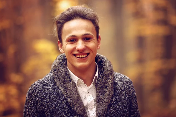 Outdoors portrait of happy young man standing in autumn park at — Stock Photo, Image