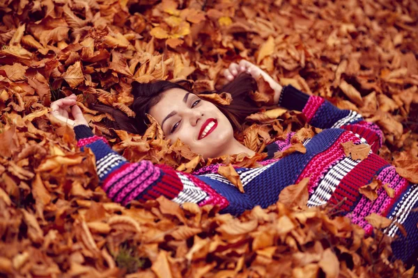 Herbstfrau liegt über Blättern und lächelt, Draufsicht — Stockfoto