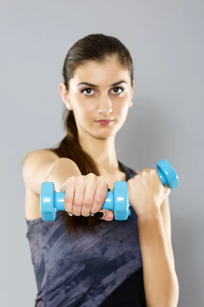 Sportliche Frau beim Workout mit Kurzhanteln, isoliert auf grauem Bac — Stockfoto