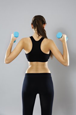 sporty woman do her workout with dumbbells, isolated on gray bac