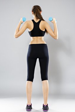 sporty woman do her workout with dumbbells, isolated on gray bac