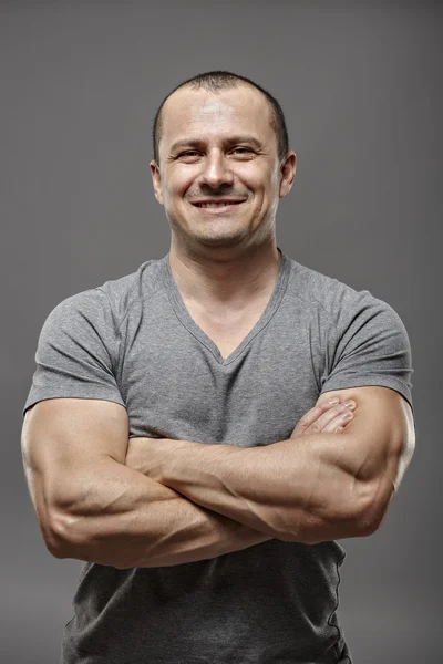Muscular man with arms crossed isolated on gray — Stock Photo, Image