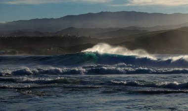 Güçlü köpüklü okyanus dalgaları Las Palmas de Gran Canaria 'daki Las Canteras ve El Confital şehir plajları boyunca kırılıyor.