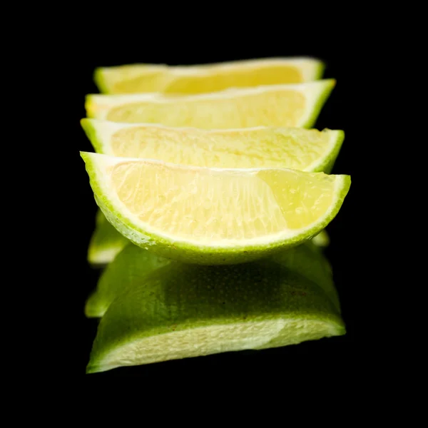 Limes on black mirror — Stock Photo, Image