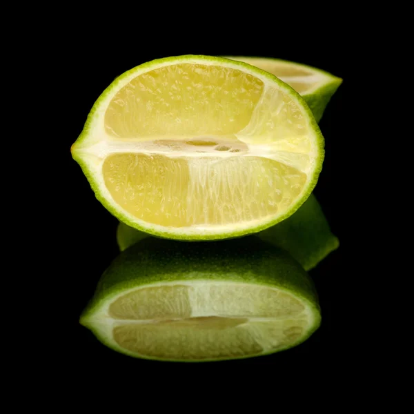 Limes on black mirror — Stock Photo, Image