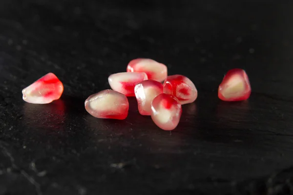 Small heap of pomegranate seeds on black slate surface — Stock Photo, Image