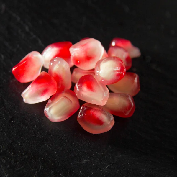 Small heap of pomegranate seeds on black slate surface — Stock Photo, Image