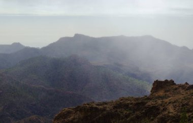 Gran Canaria, adanın merkezi manzarası, Las Cumbres, ie The Summits, Ventana del Bentayga adındaki bir kaya kemerine yürüyüş rotası, Bentayga penceresi, dağların üzerinden yağmur geliyor.