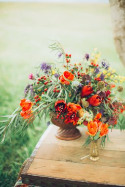 metal bir çim zemin üzerine açık havada göğsünde bir bronz vazo içinde güzel vahşi kırmızı çiçekler vardır