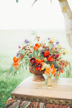 metal bir çim zemin üzerine açık havada göğsünde bir bronz vazo içinde güzel vahşi kırmızı çiçekler vardır