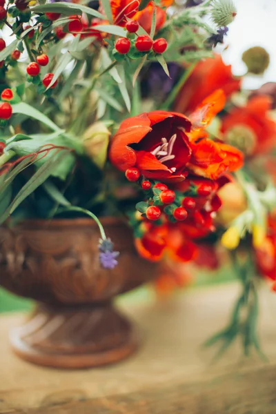 Vackra vilda röda blommor är metall i brons vas på bröstet utomhus på gräs bakgrund — Stockfoto