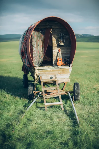 Bonito decorado cigano vagão fica em um campo em um fundo de montanhas e grama — Fotografia de Stock