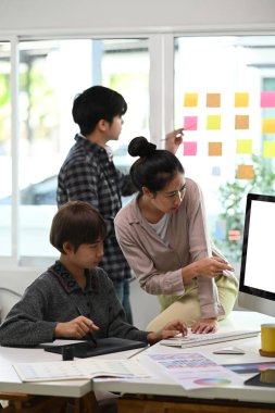 Bir grup genç tasarımcı modern ofiste yeni ürün pazarlama promosyonu için yeni yaratıcı kavramı tartışıyorlar..