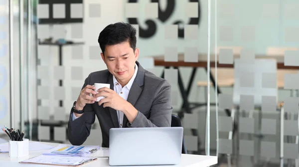 Biznesmen Trzymając Filiżankę Kawy Analizując Dane Biznesowe Online Laptopie — Zdjęcie stockowe