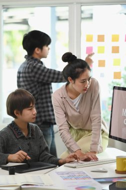 Bir grup Asyalı genç tasarımcı yaratıcı ofiste günlük kıyafet toplantısındalar..