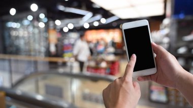 Alışveriş merkezindeki siyah beyaz ekranlı akıllı telefonu kullanan erkeklerin yakın çekim görüntüleri. Arama veya sosyal ağlar kavramı, bulanık arkaplan .