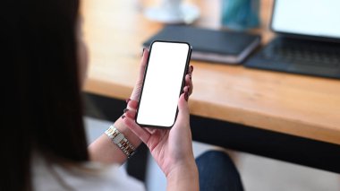 İş yerinde rahatlayan ve akıllı telefon kullanan bir kadının arka görüntüsü. Reklam metniniz için boş ekran.