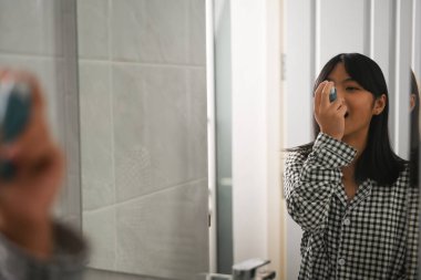 Astım spreyi kullanan astımlı genç bir kız. Astım krizi sırasında evdeki tuvalette..