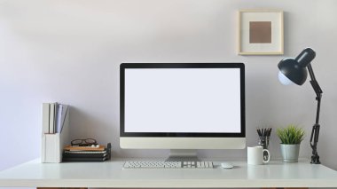 Masada beyaz ekran bilgisayar ve ofis ekipmanlarının fotoğrafı var. Modern çalışma masası konsepti.