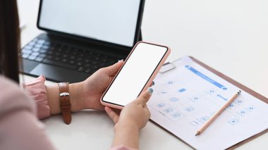 Tablet bilgisayarla çalışan ve ofis masasında cep telefonu kullanan iş kadını görüntüsünü kapat.