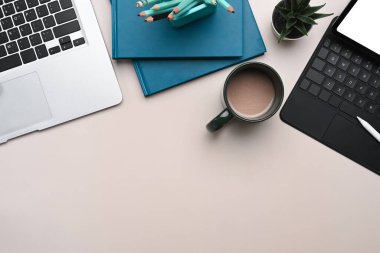 Dizüstü bilgisayarın, tabletin, defterin, kahve bardağının ve beyaz masadaki fotokopi alanının genel görüntüsü..