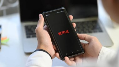 CHIANGMAI, THAILAND JAN 25 2020: Samsung Note 9 'daki Netflix uygulama simgesini açmak elinde cep telefonu ve ekranda Netflix logosu ile dinlenen adam.
