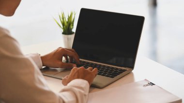 İş adamının çalışma masasındaki siyah boş ekran laptopunu kullanırken görüntüsü kesilmiş..