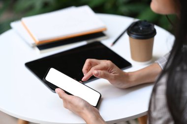 Kafede otururken akıllı telefon kullanan genç bir bayanın güvenilirliğini kapat.