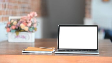 Beyaz ekran bilgisayarı, dizüstü bilgisayar, kalem ve gül buketi beyaz plastik sepetin içinde modern beton duvarlı ahşap masaya yerleştirilmiş..