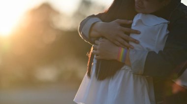 Arka planda bulanık günbatımı ışığıyla güzel parkta sarılan genç LGBT lezbiyen çifti görüntüsü. LGBT Mutluluk Çifti konsepti.