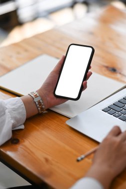 Ofiste çalışırken akıllı telefon kullanan genç bir kadının görüntüsünü kapat..