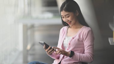 Elinde telefonuyla gülümseyen güzel bir kız. Mutluluk ofis çalışanı konsepti.