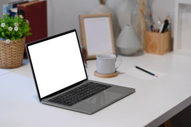 Boş ekranla dizüstü bilgisayarı, ofis malzemelerini ve kahve fincanını beyaz ofis masasına yapıştır..